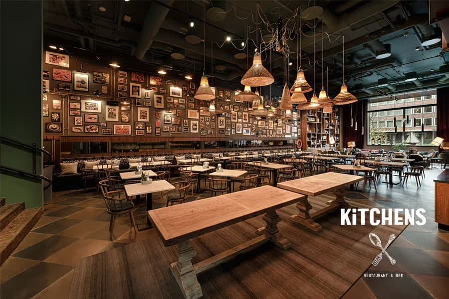 Gastraum von Kitchens in Hamburg mit langen Holztischen, Korbleuchten und Bilderwand